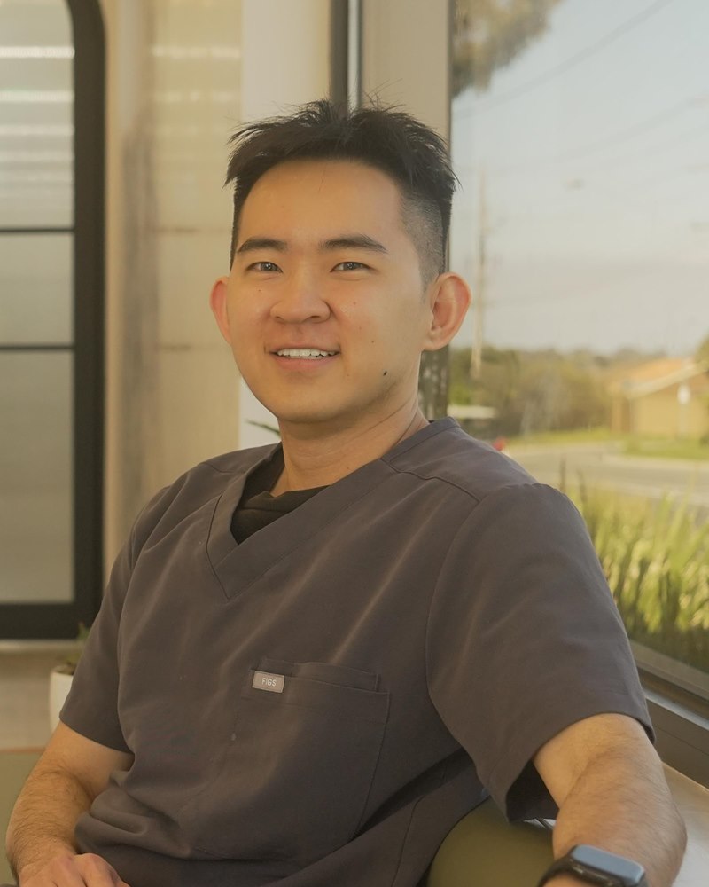 Bino Chan, Treatment Coordinator at Doncaster Hill Dental, seated beside the reception window